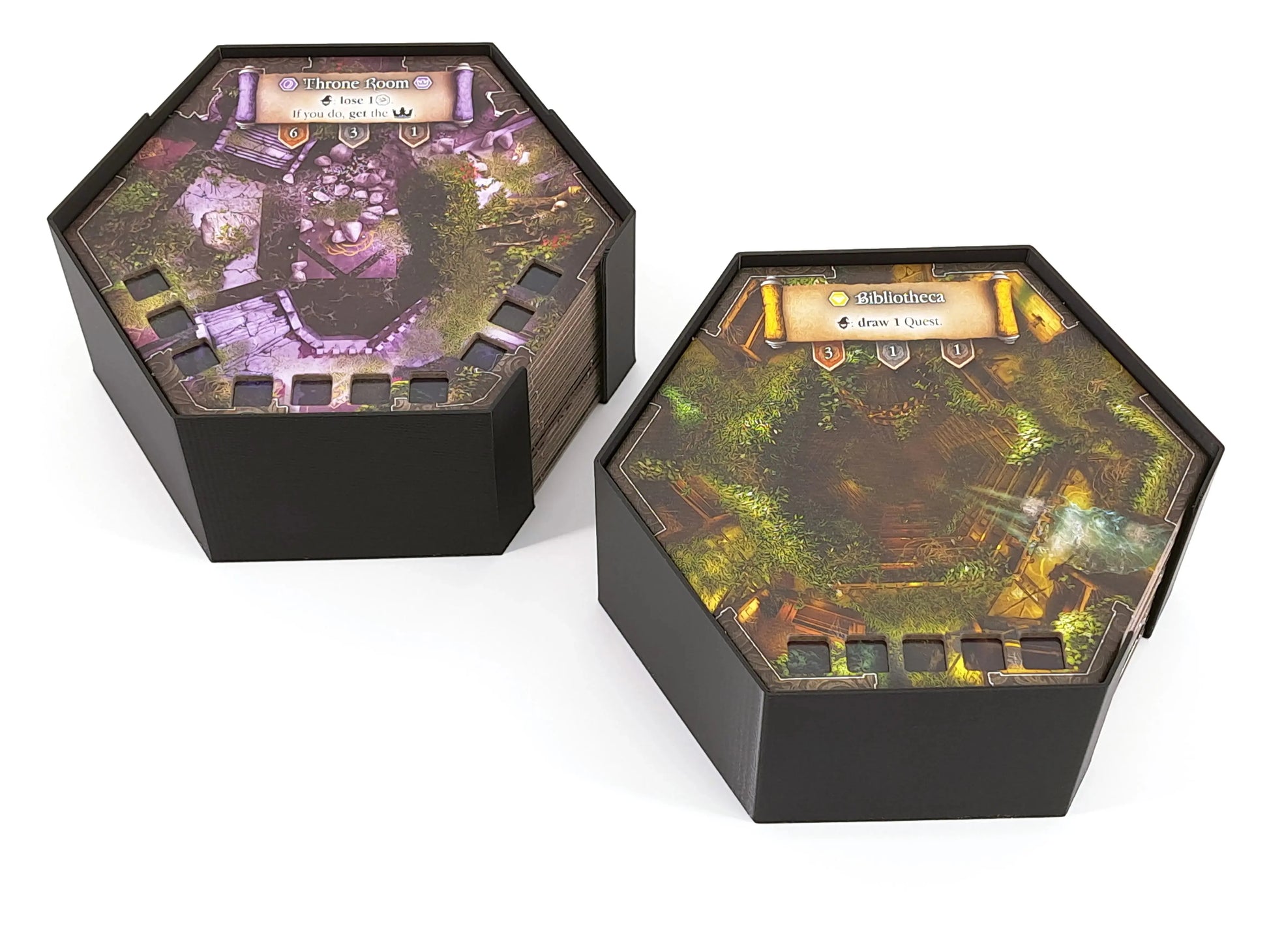 Two hexagonal board game tile holders made from black 3D printed inserts, each holding stacked map tiles with illustrated locations. Board game organizer for hex tiles by Tinkering Paws, shown outside the game box