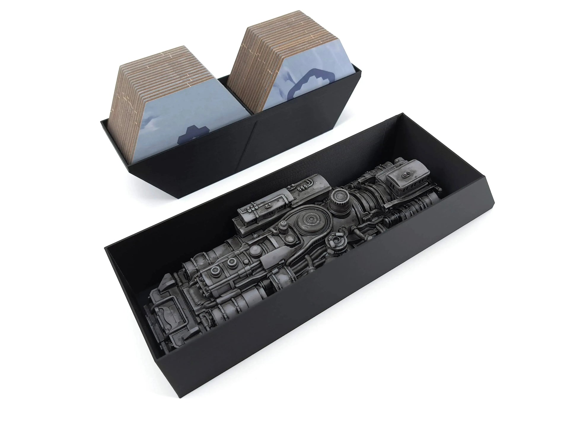 Two black insert trays: the top tray holds two stacks of hexagonal cardboard map tiles; the bottom tray holds a large, highly detailed grey plastic miniature of the Steam Generator.