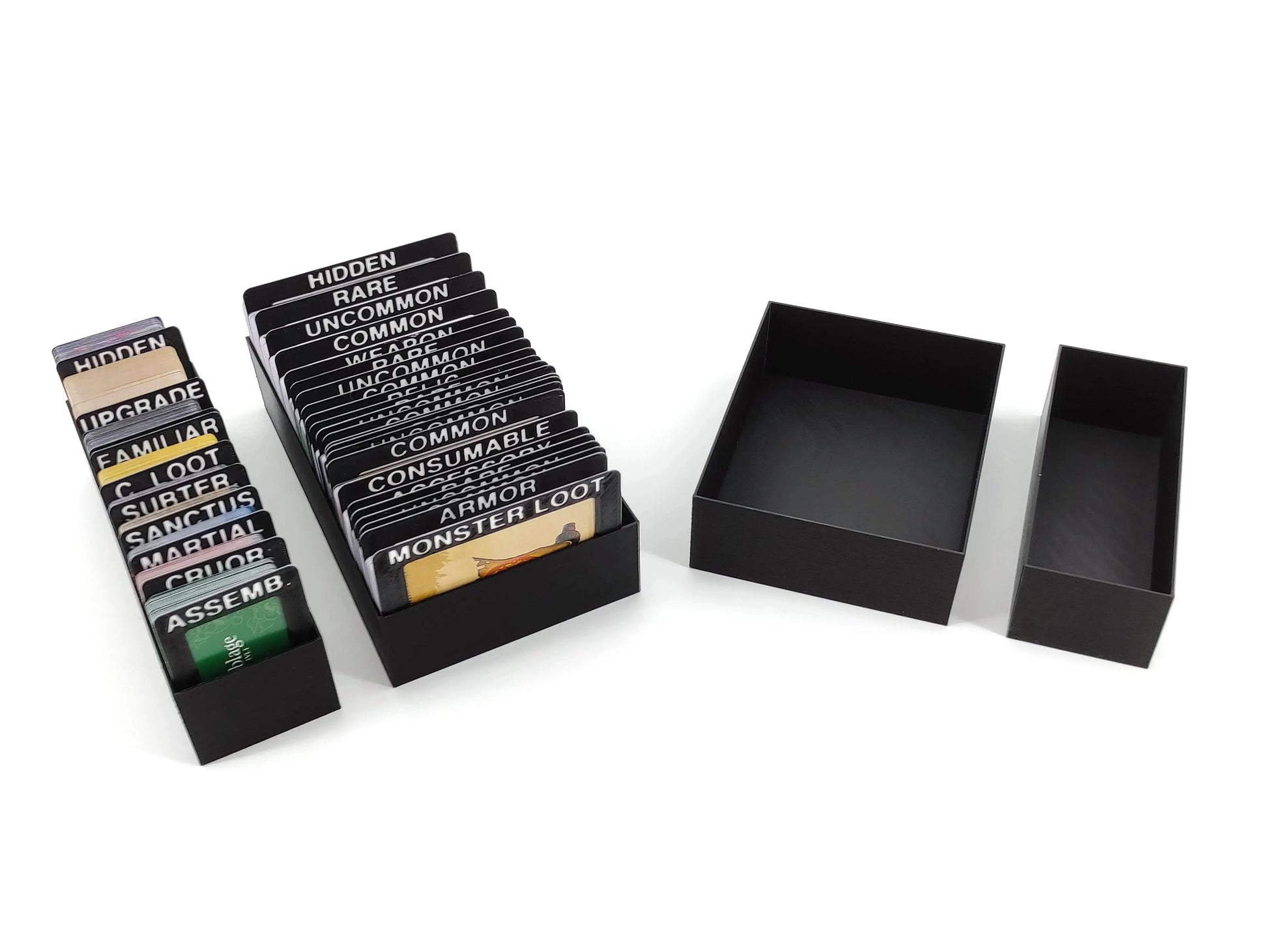 Four modular black trays for Middara board game components, organized with colorful dice, cardboard tokens, and small circular game markers.