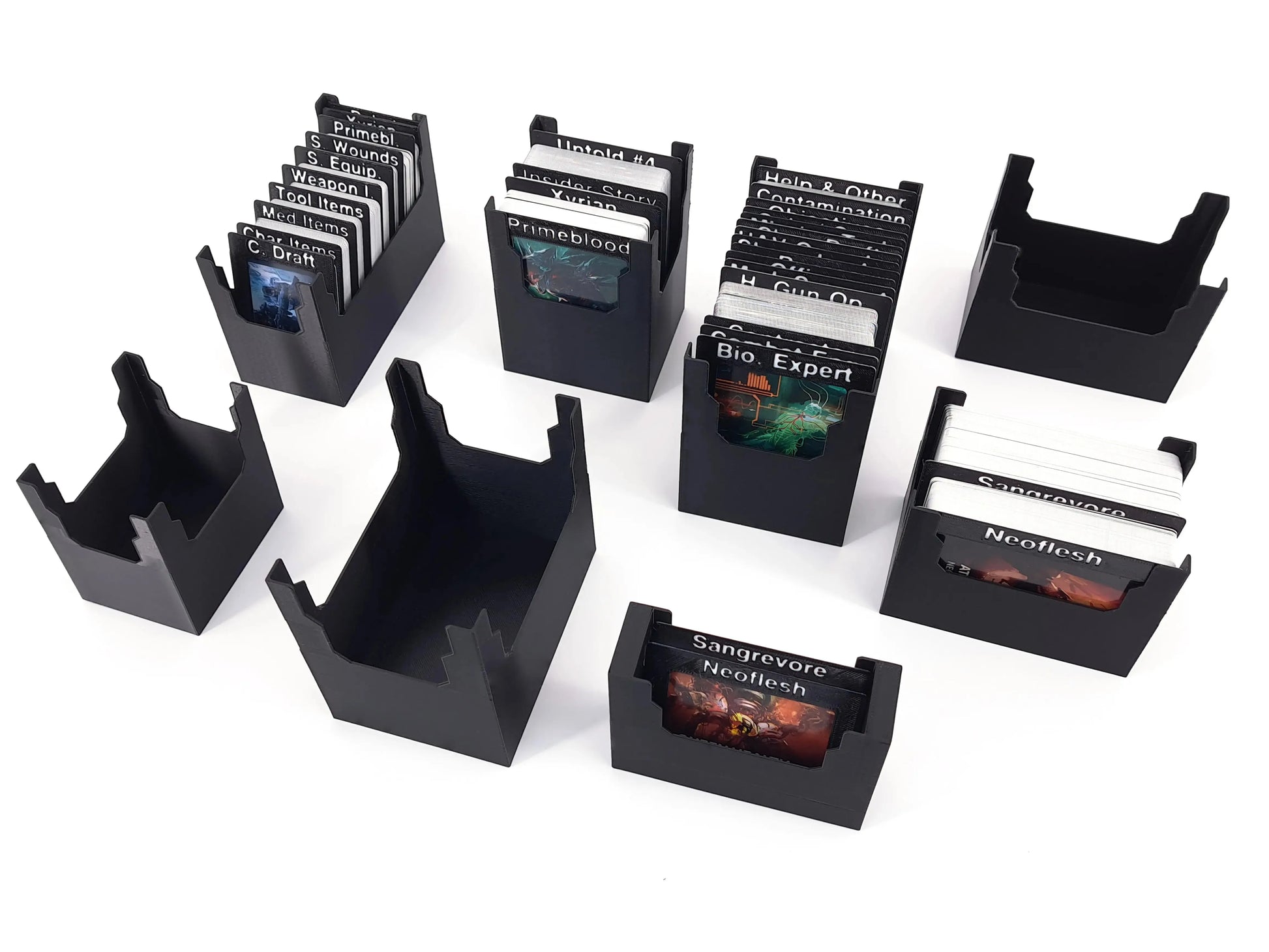 Mehrere 3D-gedruckte Kartenhalter für das Brettspiel Nemesis: verschiedene Deck-Organizer in Schwarz, jeweils mit sortierten Karten wie Primeblood, Bio Expert oder Neoflesh. Leere Halter sind ebenfalls zu sehen, alle in modularer Bauweise zur übersichtlichen Aufbewahrung der Spielkarten.