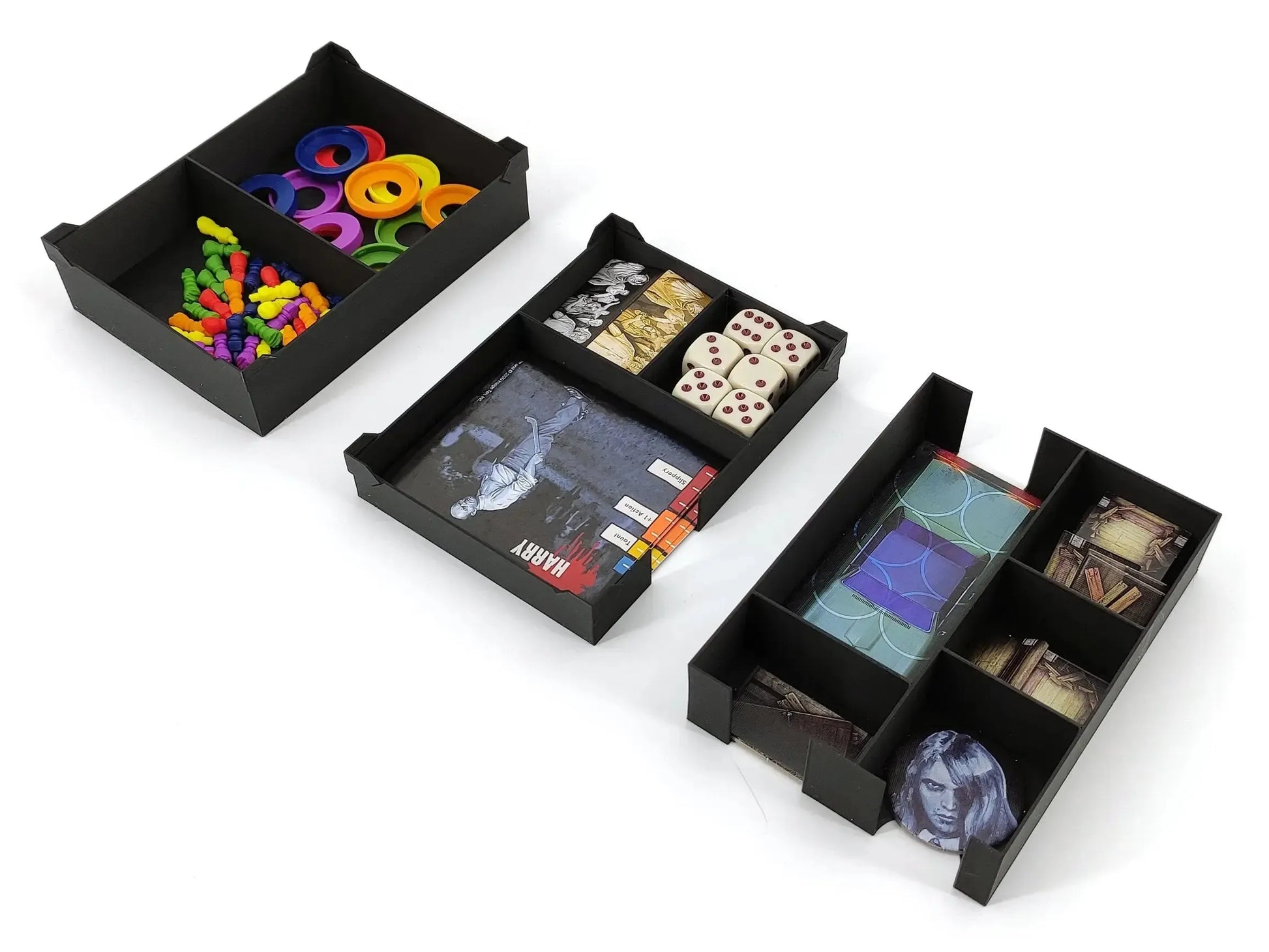 Three black organizer trays for Night of the Living Dead containing dice, cardboard tokens, character dashboards, and small plastic player pieces.