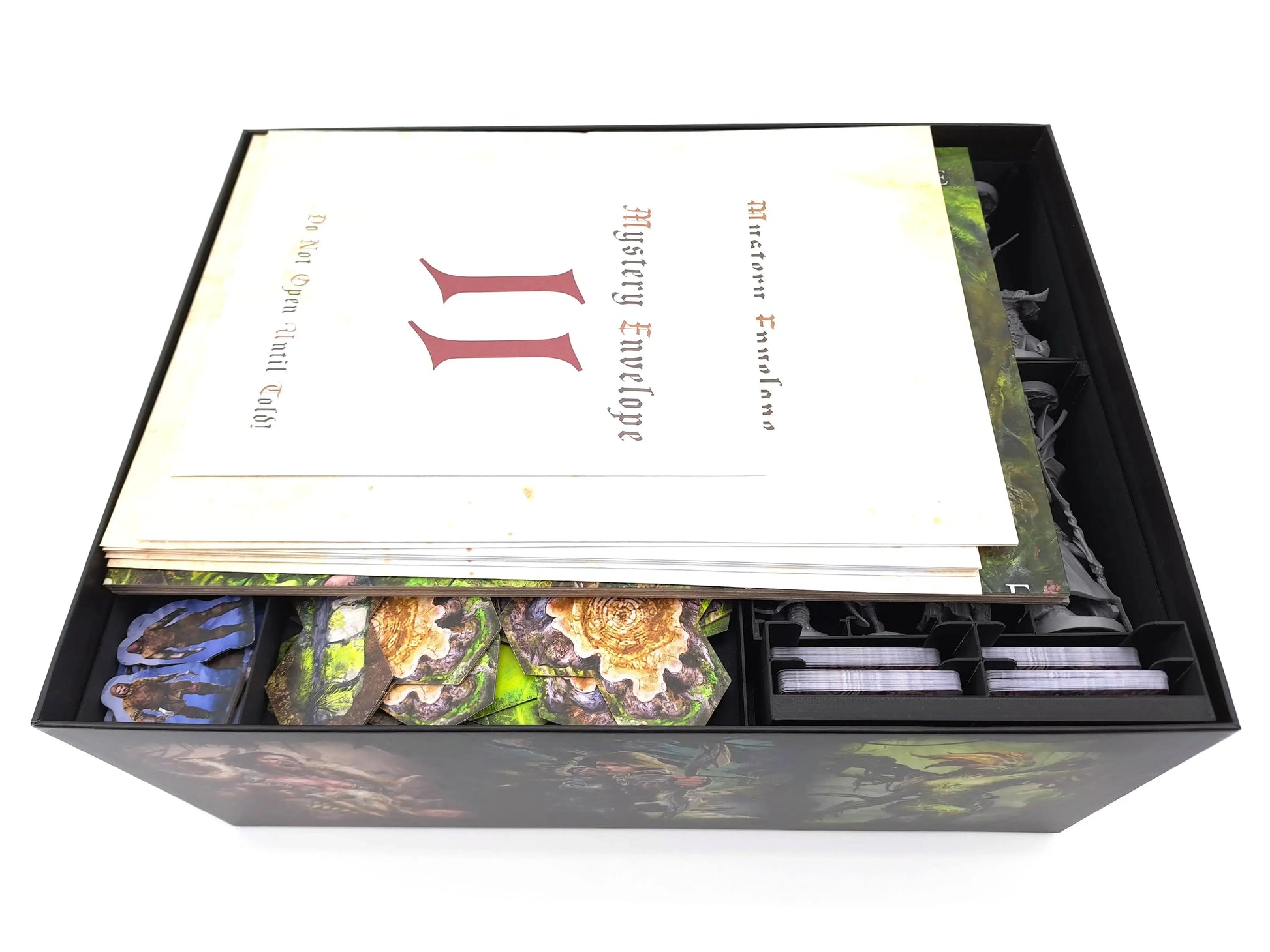 Oathsworn game box fully packed with Tinkering Paws 3D-printed insert trays. Mystery Envelopes and scenario books rest on top of organized terrain tiles, cards, and miniatures. This 3D-print upgrade provides space-saving storage, fast set-up, easy clean-up, and keeps all expansions and components neatly arranged.