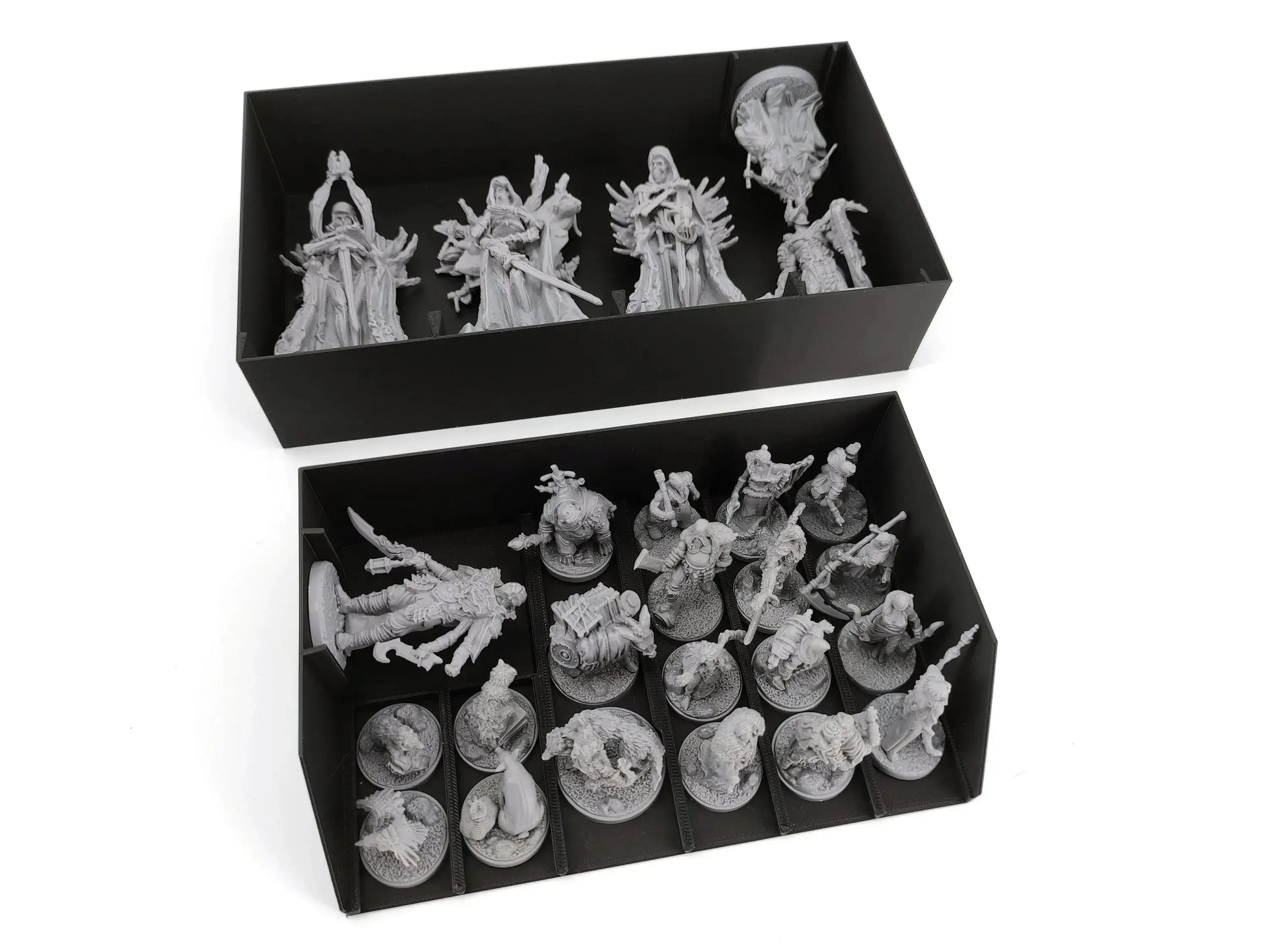 Two black boxes with organizer inserts showing a collection of unpainted grey miniatures for a fantasy board game. The top box contains four large, intricately sculpted figures standing upright. The bottom box contains smaller figures mounted on round bases, including a larger, reclining monster, all sorted into neat compartments.