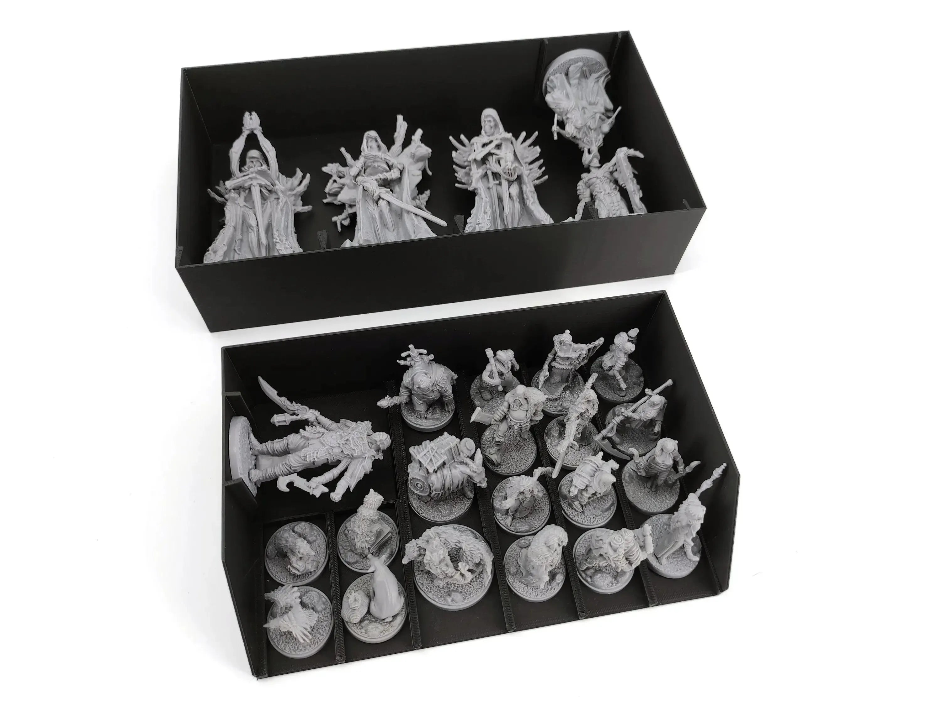 Two black boxes with organizer inserts showing a collection of unpainted grey miniatures for a fantasy board game. The top box contains four large, intricately sculpted figures standing upright. The bottom box contains smaller figures mounted on round bases, including a larger, reclining monster, all sorted into neat compartments.