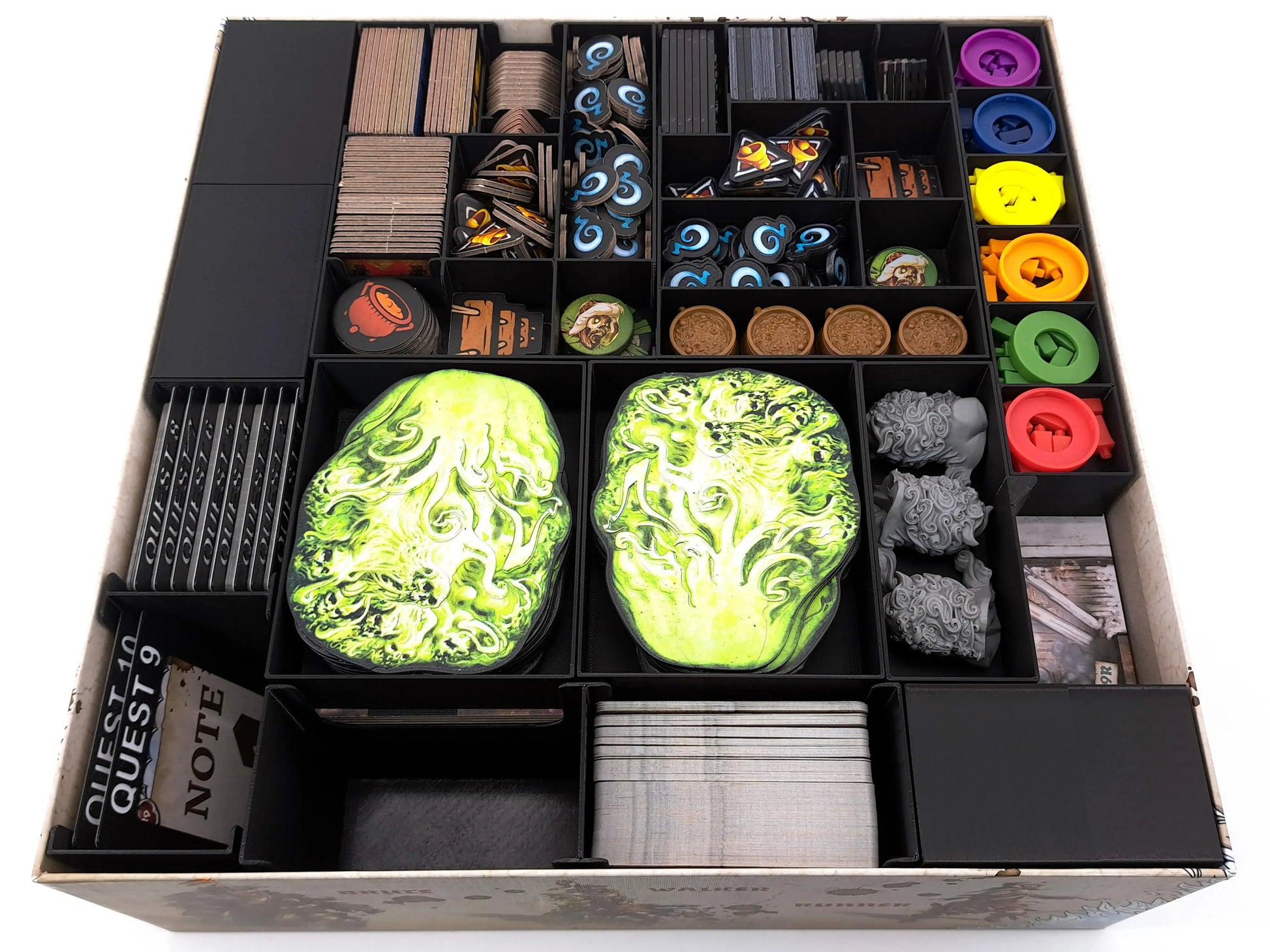 Top-down view of a fully organized Zombicide White Death game box using a 3D-printed board game insert. The black modular organizers neatly store cards, tokens, tiles, dice, colored player components, and large green objective tiles. The digital STL insert keeps all components separated, visible, and easy to access inside the box.