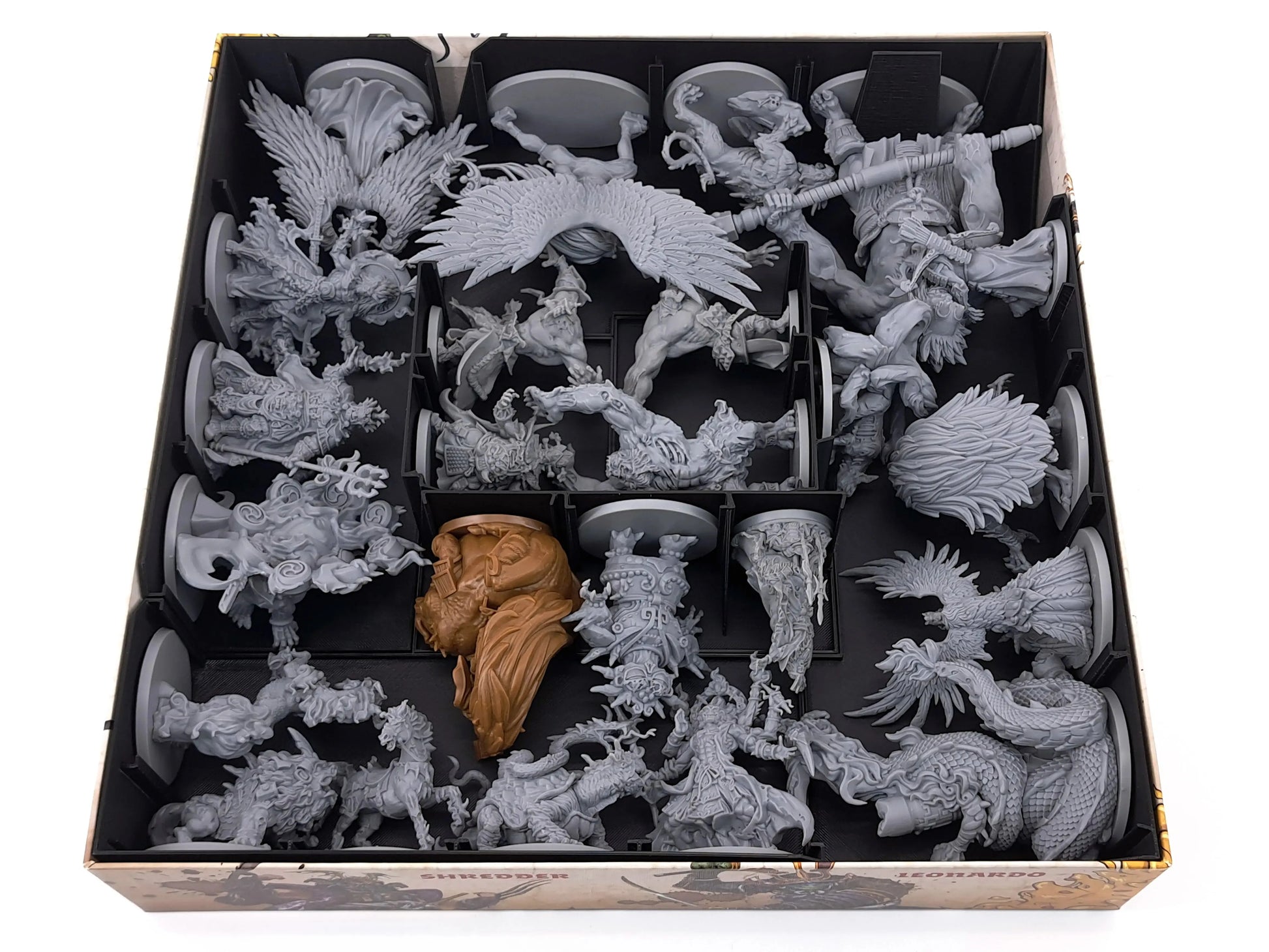 Top-down view of a Zombicide White Death game box showing a 3D-printed miniature storage insert. The black organizer securely holds large and detailed monster and hero miniatures, including winged and oversized figures, each separated into individual compartments. The digital STL board game insert protects miniatures and keeps the box neatly organized.